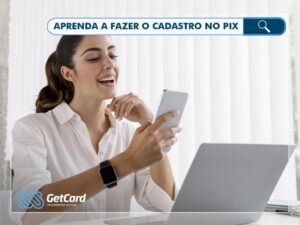 mulher em frente ao computador com um celular na mão