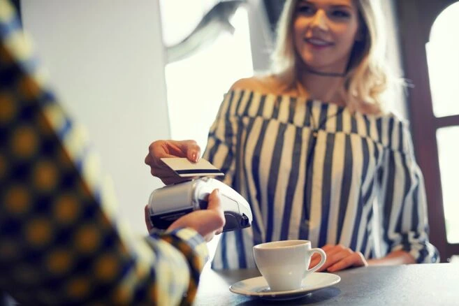 Mulher pagando conta em restaurante com cartão.