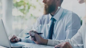 Executivos em reunião analisando gráfico de crescimento digital sobreposto a notebook em ambiente de escritório iluminado.